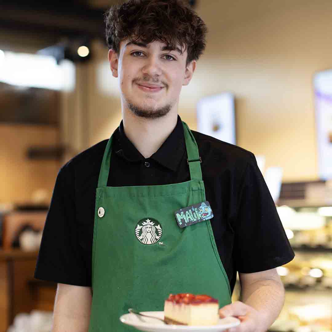 Employee from Starbucks in Frederiksberg holding a strawberry cake.